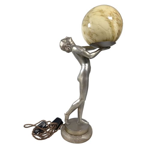 An Art Deco spelter table lamp featuring a silvered female figure holding up an amber glass globe shade on a circular onyx base. View II