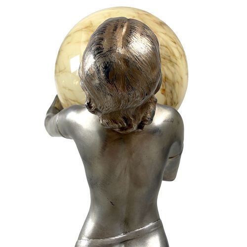 An Art Deco spelter table lamp featuring a silvered female figure holding up an amber glass globe shade on a circular onyx base. View XI