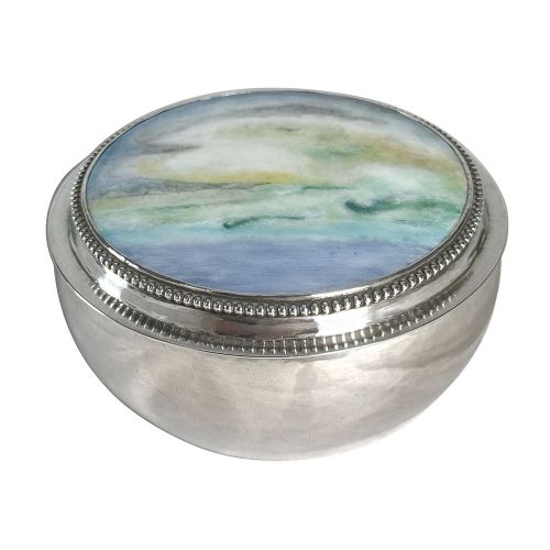 A circular Arts and Crafts sterling silver box featuring a hand-painted enamel landscape plaque inset on the lid with a beaded silver border. View IV