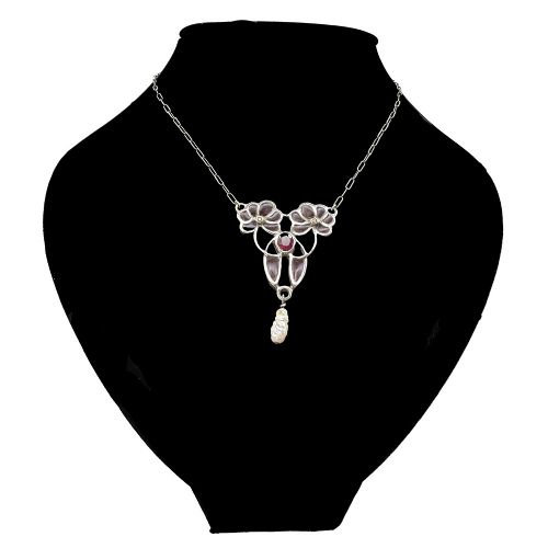 An Art Nouveau silver chain necklace featuring a stylized floral pendant inlaid with dark red enamel, a central ruby, and a pearl drop. View II