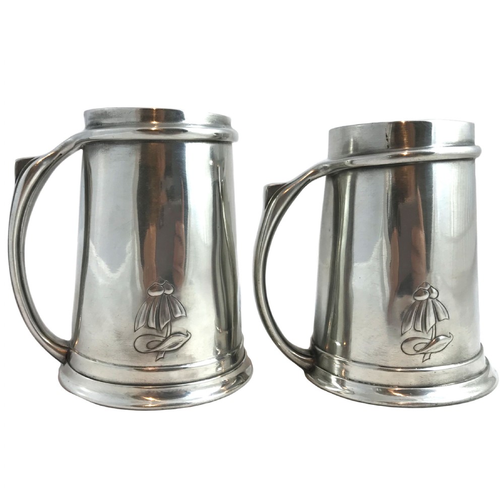A pair of tapered pewter tankards with stylised floral relief motifs near the base and curved loop handles. View II