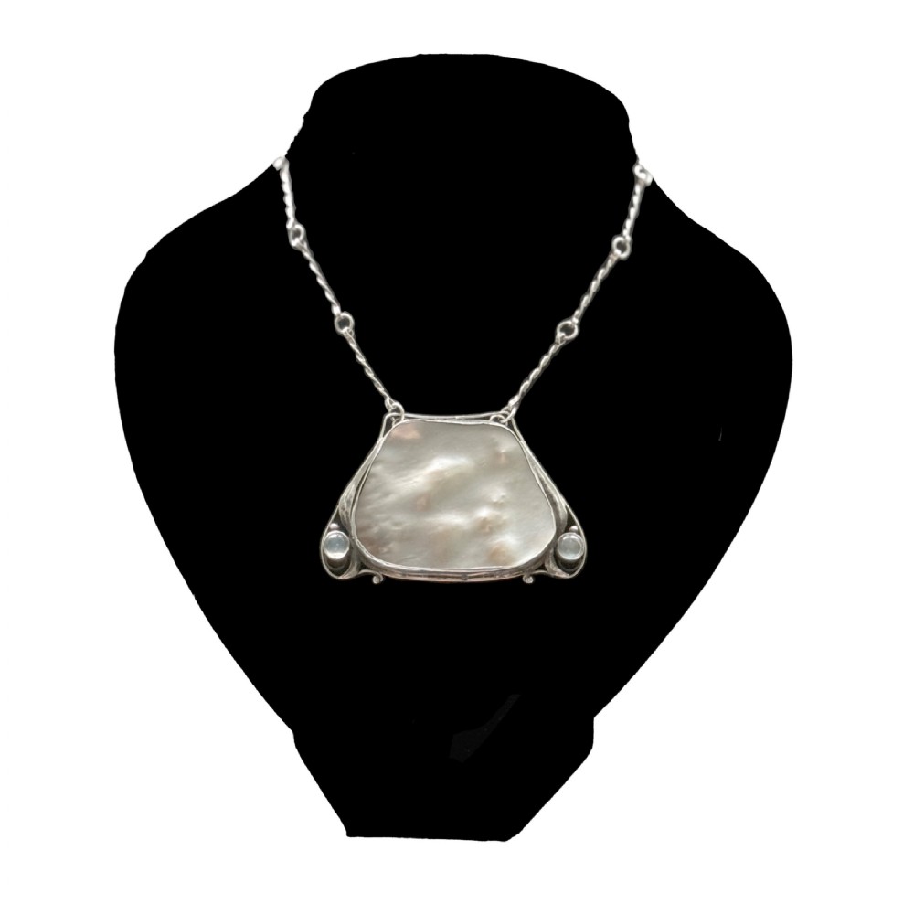 An Arts and Crafts silver pendant featuring a central trapezoidal blister pearl flanked by two round cabochon moonstones, attached to a twisted silver link chain.