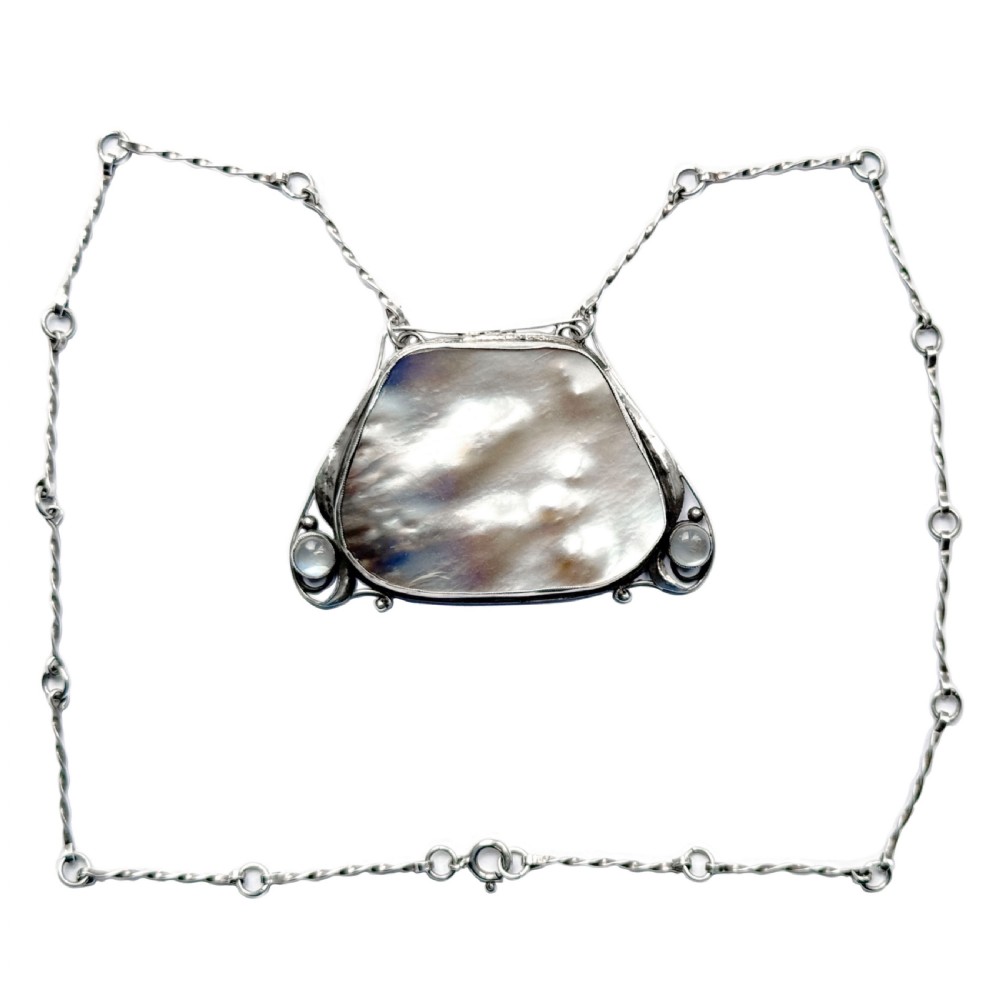 An Arts and Crafts silver pendant featuring a central trapezoidal blister pearl flanked by two round cabochon moonstones, attached to a twisted silver link chain. View III