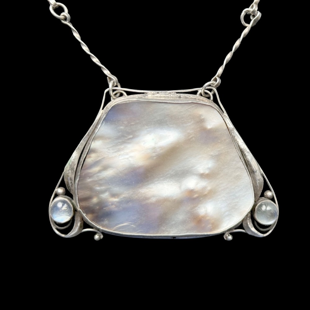 An Arts and Crafts silver pendant featuring a central trapezoidal blister pearl flanked by two round cabochon moonstones, attached to a twisted silver link chain. View V