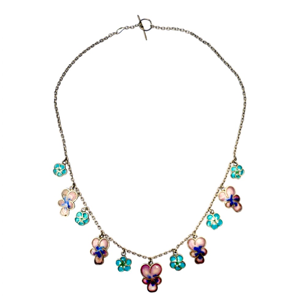 An antique silver necklace featuring dangling enamel pansy flower charms suspended from a delicate chain.