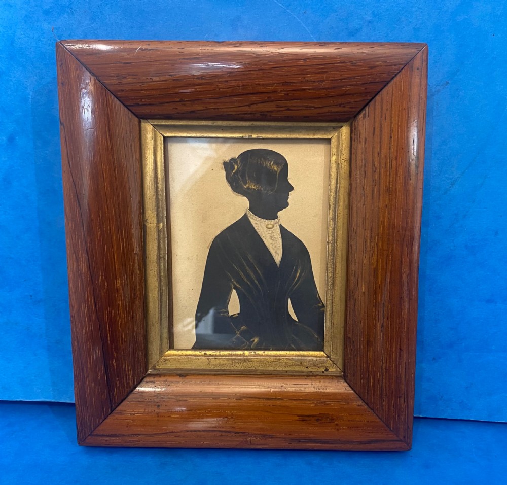 A Victorian profile silhouette portrait of a woman with detailed bronzed hair and collar, framed in a wide rosewood frame with a gilded inner slip. View II
