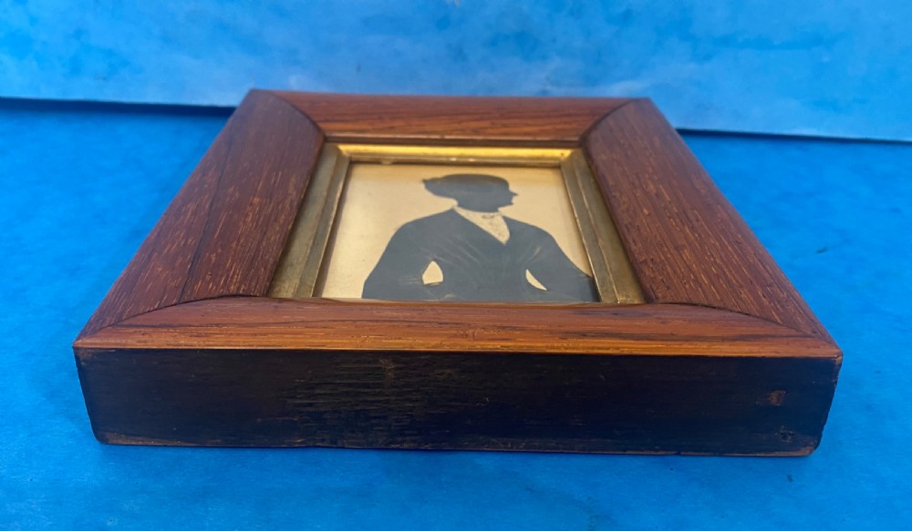 A Victorian profile silhouette portrait of a woman with detailed bronzed hair and collar, framed in a wide rosewood frame with a gilded inner slip. View III