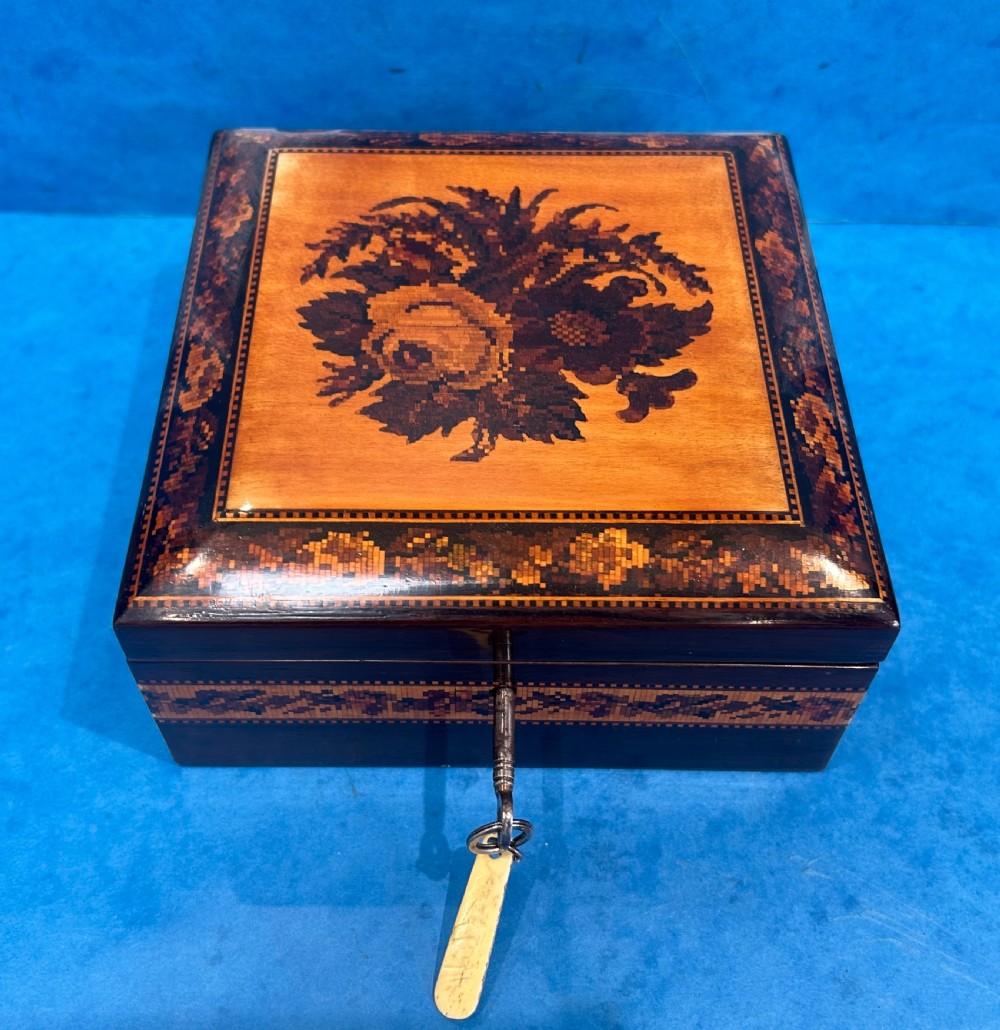A square Victorian wooden box featuring a central floral mosaic inlay panel, detailed geometric mosaic borders, and a metal key. View III