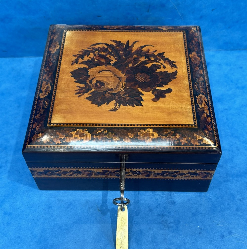 A square Victorian wooden box featuring a central floral mosaic inlay panel, detailed geometric mosaic borders, and a metal key. View XI