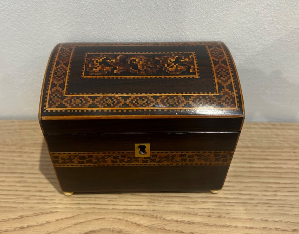 A Victorian rosewood tea caddy featuring a domed lid, geometric mosaic wood inlay, and a brass keyhole escutcheon. View III
