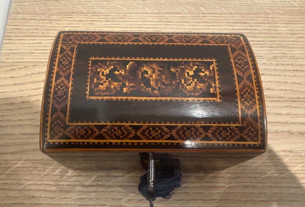 A Victorian rosewood tea caddy featuring a domed lid, geometric mosaic wood inlay, and a brass keyhole escutcheon. View VII