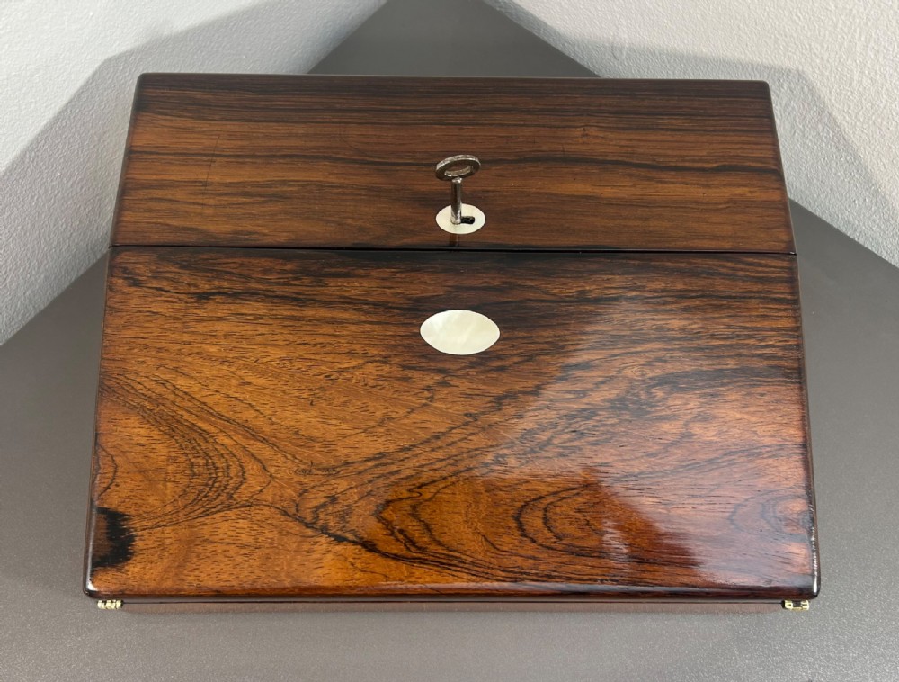 A William IV rosewood lap desk featuring a brass keyhole escutcheon with key inserted and a circular brass inlay on its sloped lid. View II