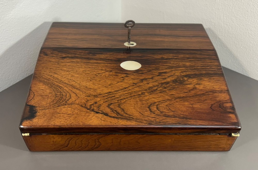 A William IV rosewood lap desk featuring a brass keyhole escutcheon with key inserted and a circular brass inlay on its sloped lid. View III