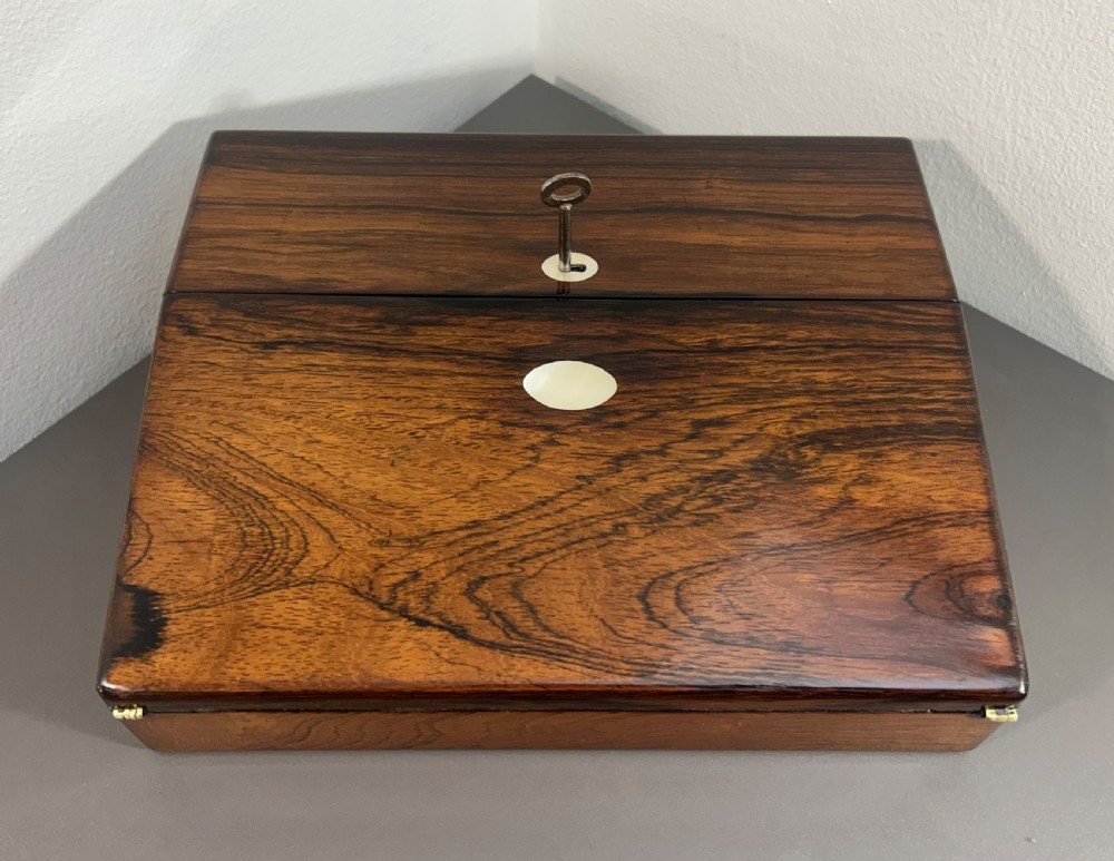 A William IV rosewood lap desk featuring a brass keyhole escutcheon with key inserted and a circular brass inlay on its sloped lid. View VI