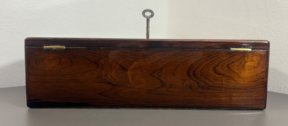 A William IV rosewood lap desk featuring a brass keyhole escutcheon with key inserted and a circular brass inlay on its sloped lid. View VII