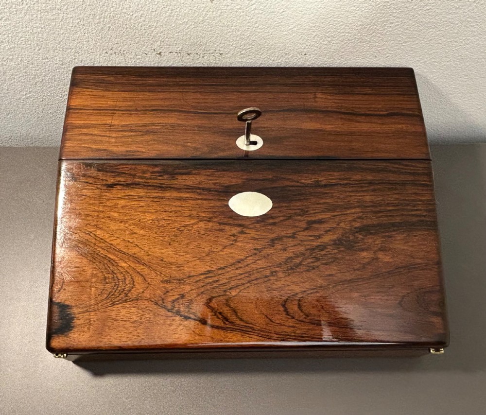 A William IV rosewood lap desk featuring a brass keyhole escutcheon with key inserted and a circular brass inlay on its sloped lid. View IX