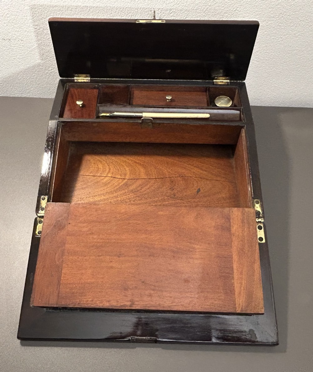 A William IV rosewood lap desk featuring a brass keyhole escutcheon with key inserted and a circular brass inlay on its sloped lid. View XIV