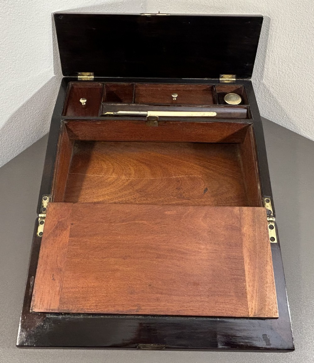 A William IV rosewood lap desk featuring a brass keyhole escutcheon with key inserted and a circular brass inlay on its sloped lid. View XV