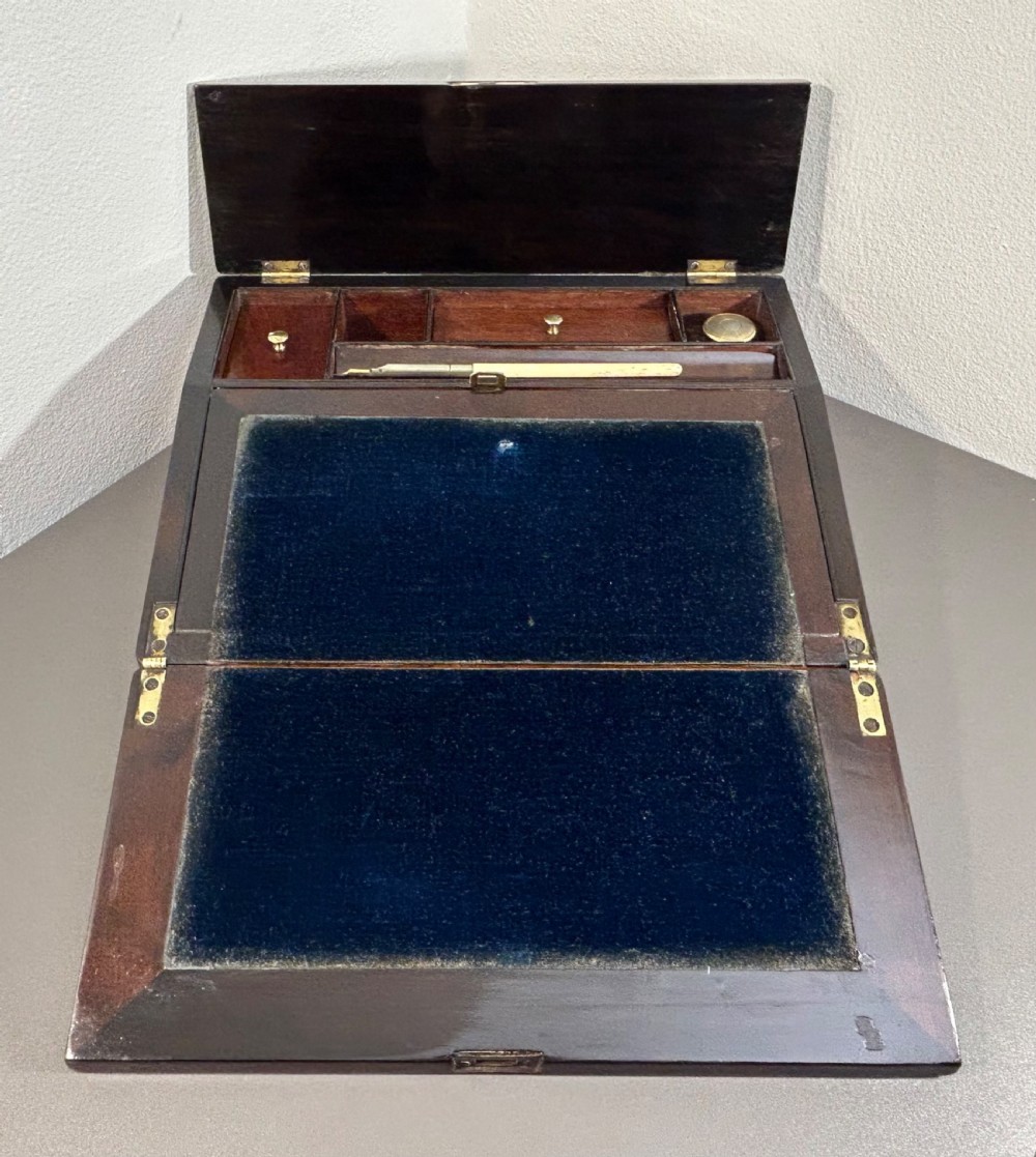 A William IV rosewood lap desk featuring a brass keyhole escutcheon with key inserted and a circular brass inlay on its sloped lid. View XVI
