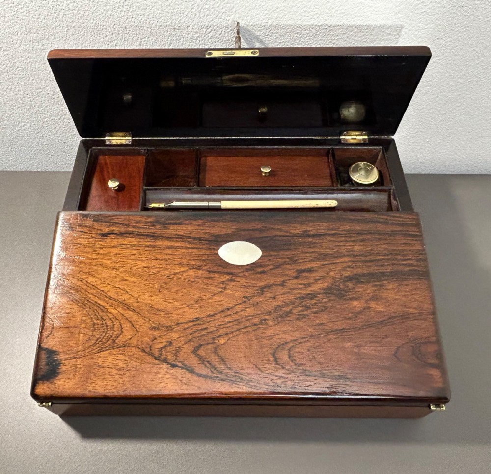 A William IV rosewood lap desk featuring a brass keyhole escutcheon with key inserted and a circular brass inlay on its sloped lid. View XVII