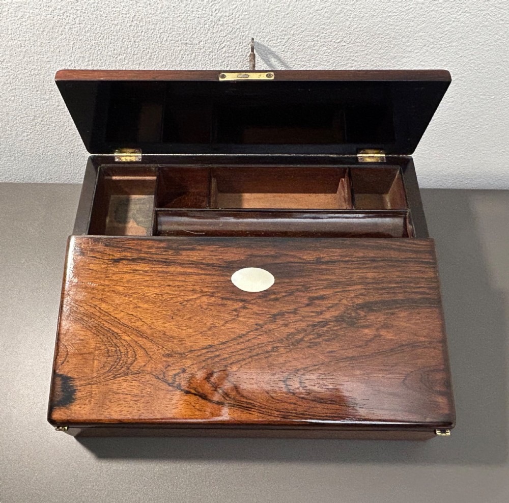 A William IV rosewood lap desk featuring a brass keyhole escutcheon with key inserted and a circular brass inlay on its sloped lid. View XIX