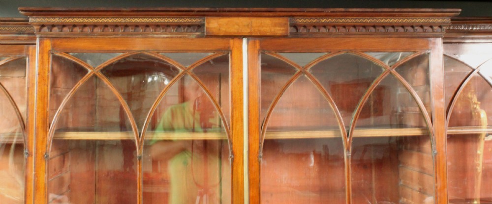 A large George III mahogany breakfront bookcase with glazed upper doors featuring Gothic astragal glazing bars and panelled lower cupboard doors. View III