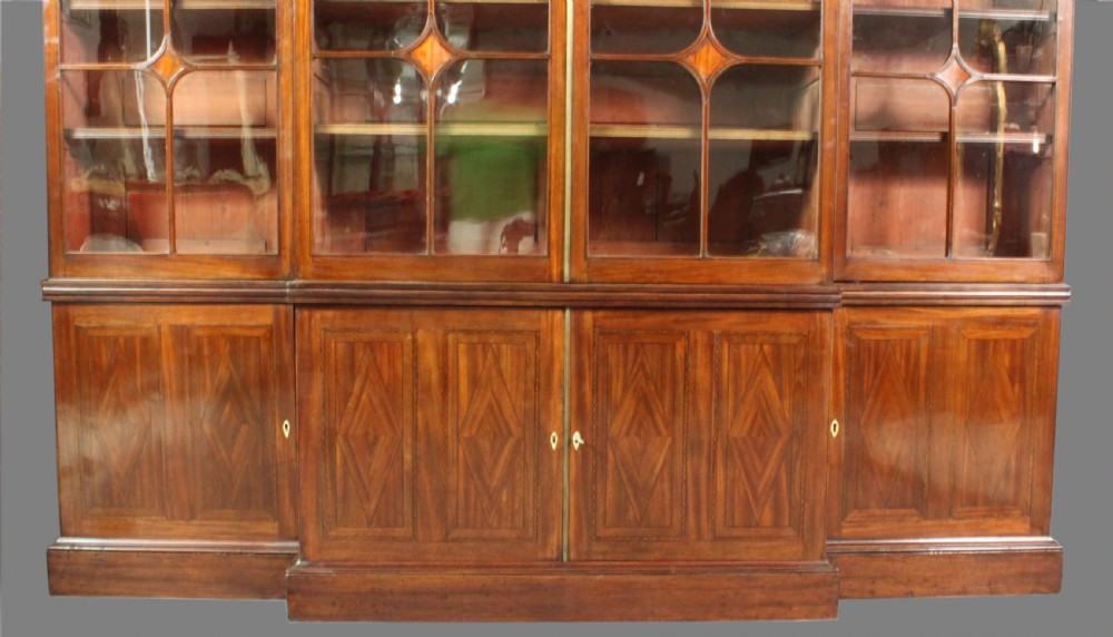 A large George III mahogany breakfront bookcase with glazed upper doors featuring Gothic astragal glazing bars and panelled lower cupboard doors. View VI