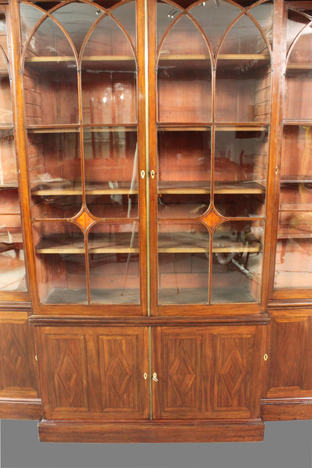 A large George III mahogany breakfront bookcase with glazed upper doors featuring Gothic astragal glazing bars and panelled lower cupboard doors. View VII
