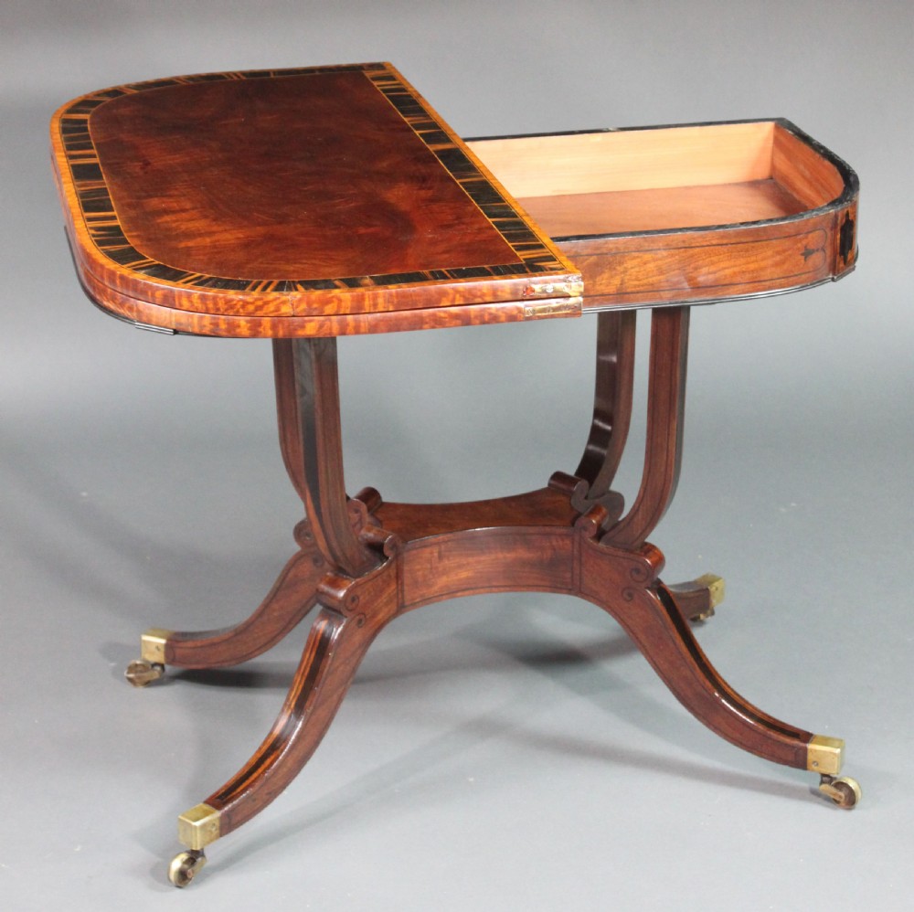 A matching three-piece Regency period furniture set featuring a central sofa table with drawers flanked by a pair of D-shaped folding card tables, all crafted with figured wood and crossbanded inlay borders on curved legs with brass castors. View VII