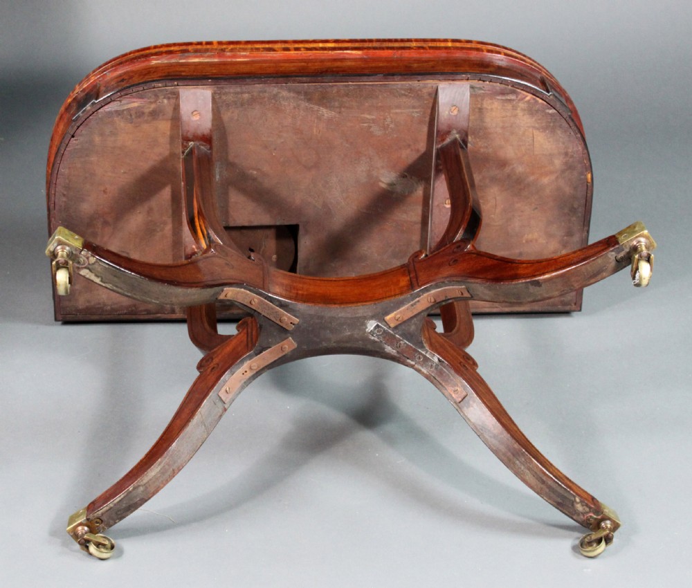 A matching three-piece Regency period furniture set featuring a central sofa table with drawers flanked by a pair of D-shaped folding card tables, all crafted with figured wood and crossbanded inlay borders on curved legs with brass castors. View IX