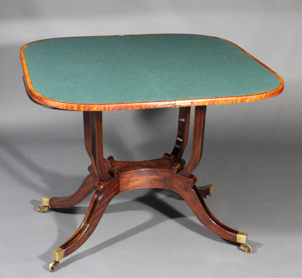 A matching three-piece Regency period furniture set featuring a central sofa table with drawers flanked by a pair of D-shaped folding card tables, all crafted with figured wood and crossbanded inlay borders on curved legs with brass castors. View X
