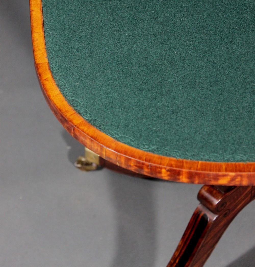 A matching three-piece Regency period furniture set featuring a central sofa table with drawers flanked by a pair of D-shaped folding card tables, all crafted with figured wood and crossbanded inlay borders on curved legs with brass castors. View XI