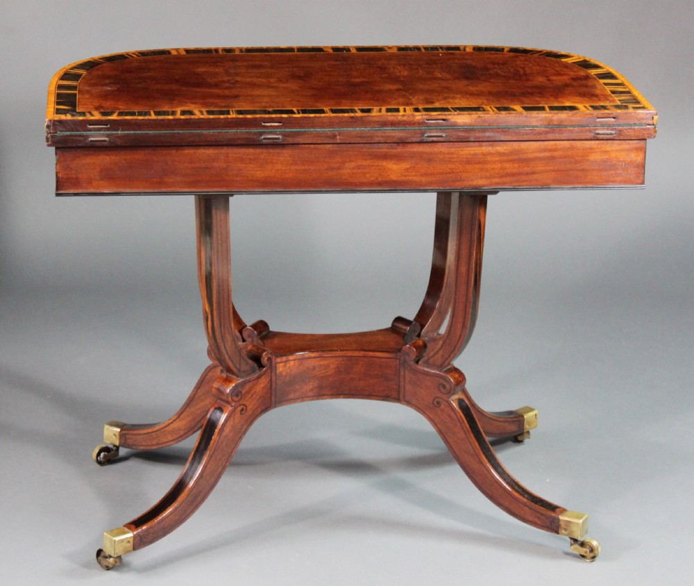 A matching three-piece Regency period furniture set featuring a central sofa table with drawers flanked by a pair of D-shaped folding card tables, all crafted with figured wood and crossbanded inlay borders on curved legs with brass castors. View XII