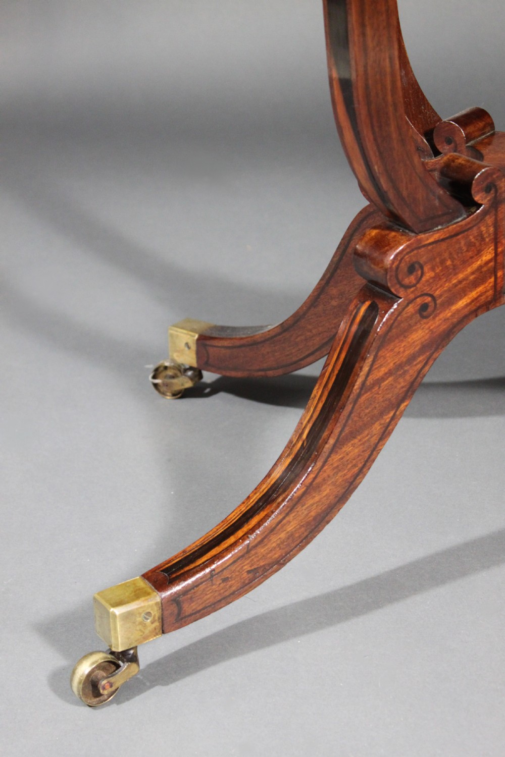 A matching three-piece Regency period furniture set featuring a central sofa table with drawers flanked by a pair of D-shaped folding card tables, all crafted with figured wood and crossbanded inlay borders on curved legs with brass castors. View XIII