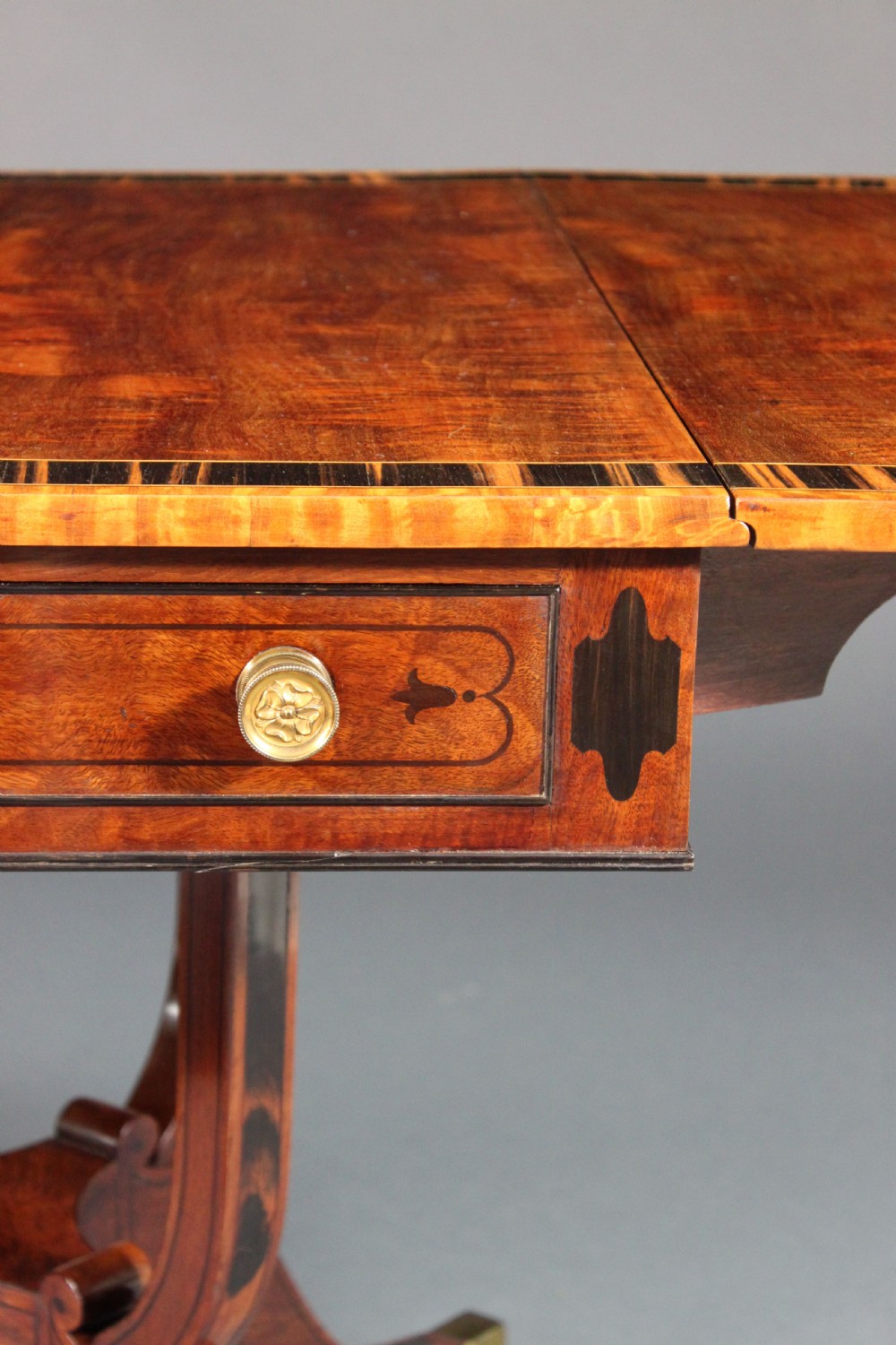A matching three-piece Regency period furniture set featuring a central sofa table with drawers flanked by a pair of D-shaped folding card tables, all crafted with figured wood and crossbanded inlay borders on curved legs with brass castors. View XVII