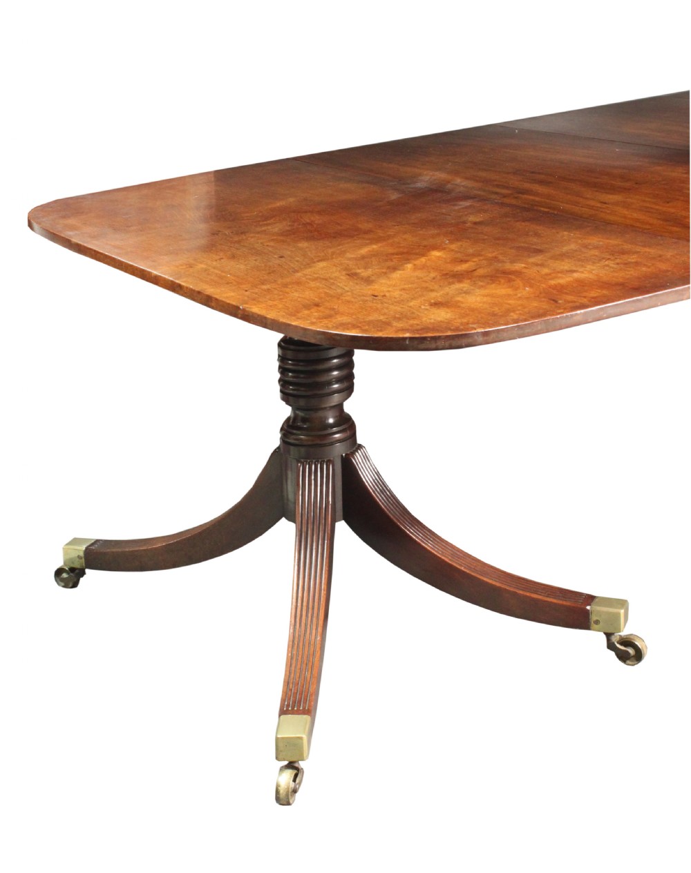 An antique mahogany twin pedestal dining table with rounded corners, reeded splayed legs, and brass castors. View III