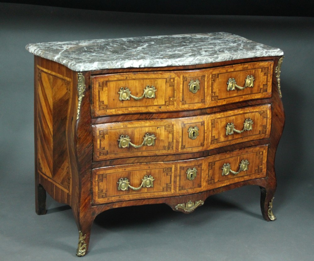 A Louis XV style kingwood commode featuring three drawers with geometric parquetry inlay, gilt bronze mounts, and a shaped grey marble top.