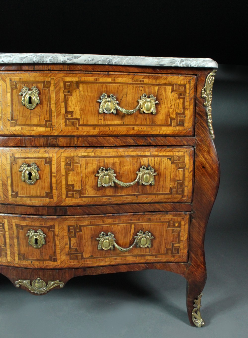 A Louis XV style kingwood commode featuring three drawers with geometric parquetry inlay, gilt bronze mounts, and a shaped grey marble top. View III