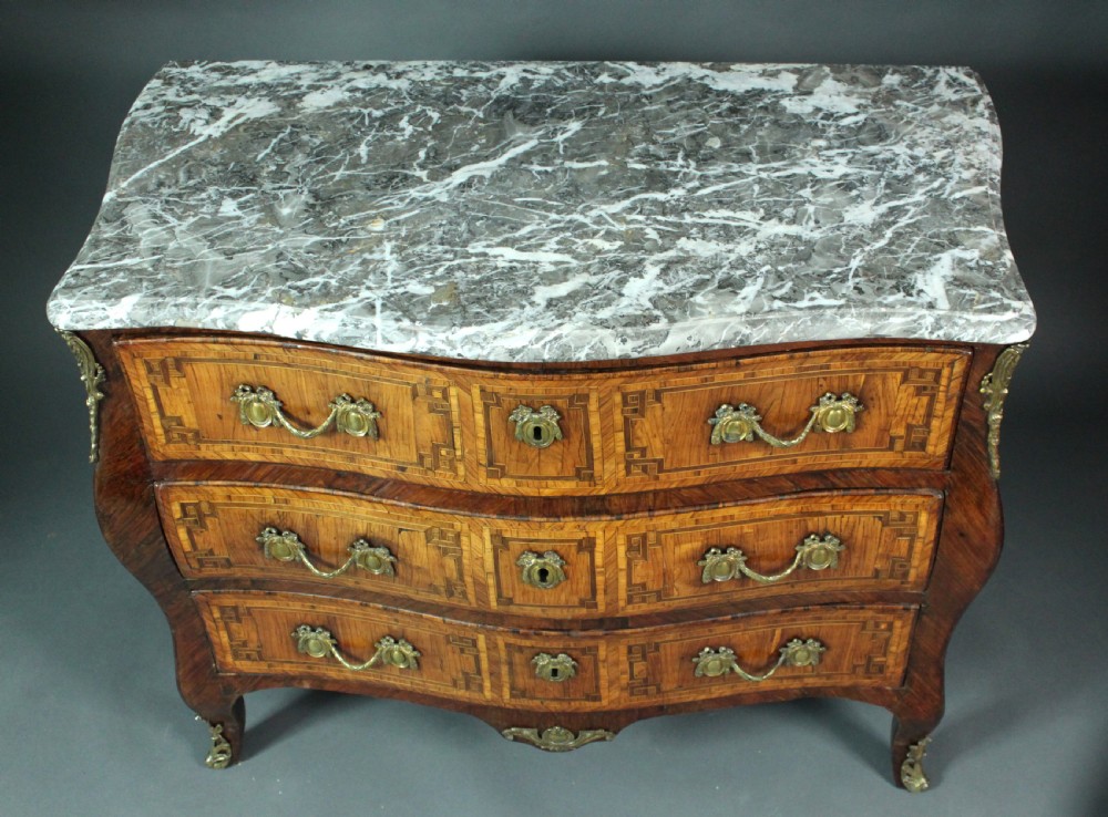A Louis XV style kingwood commode featuring three drawers with geometric parquetry inlay, gilt bronze mounts, and a shaped grey marble top. View VII