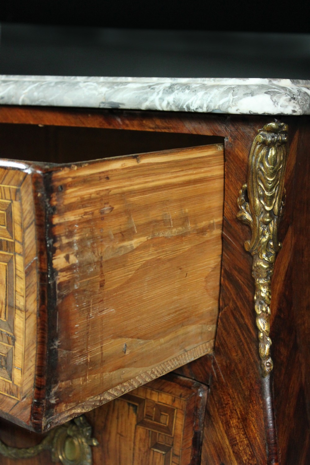 A Louis XV style kingwood commode featuring three drawers with geometric parquetry inlay, gilt bronze mounts, and a shaped grey marble top. View XI