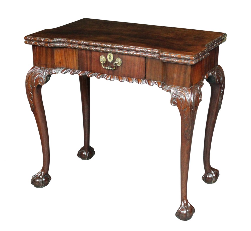 An antique Chippendale mahogany fold-over card table with cabriole legs, carved ball and claw feet, and a single drawer with brass hardware.
