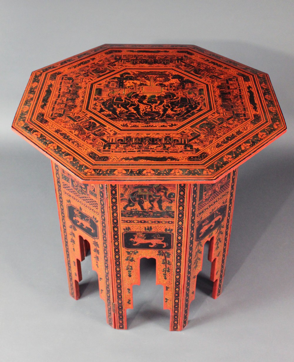 An octagonal red lacquer side table decorated with black hand-painted figures, elephants, and geometric borders. View II