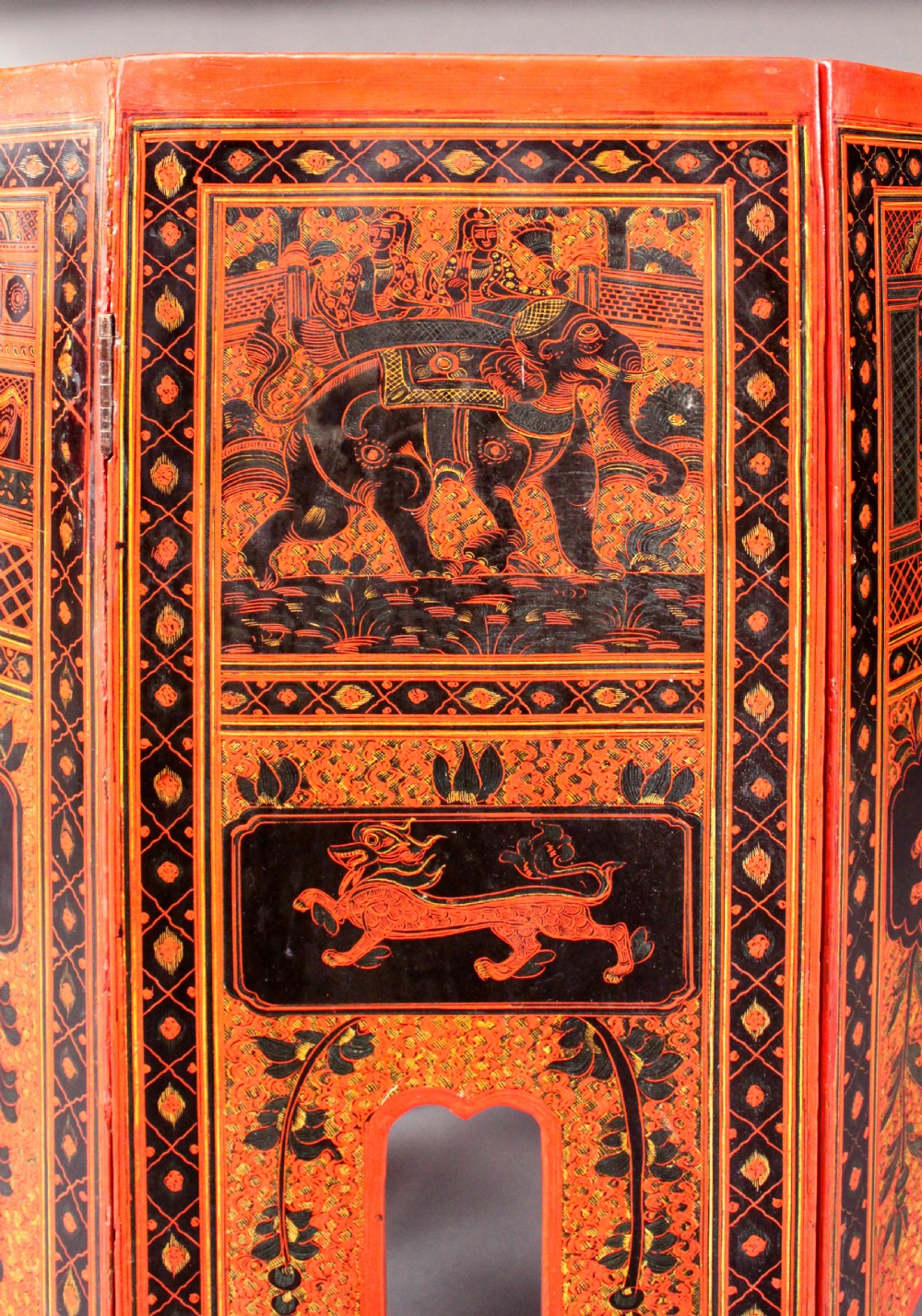 An octagonal red lacquer side table decorated with black hand-painted figures, elephants, and geometric borders. View IV