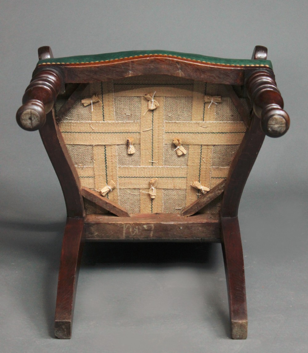 A pair of carved dark oak Gothic Revival hall armchairs featuring pointed arch backrests with painted armorial crests and green leather seats. View VIII