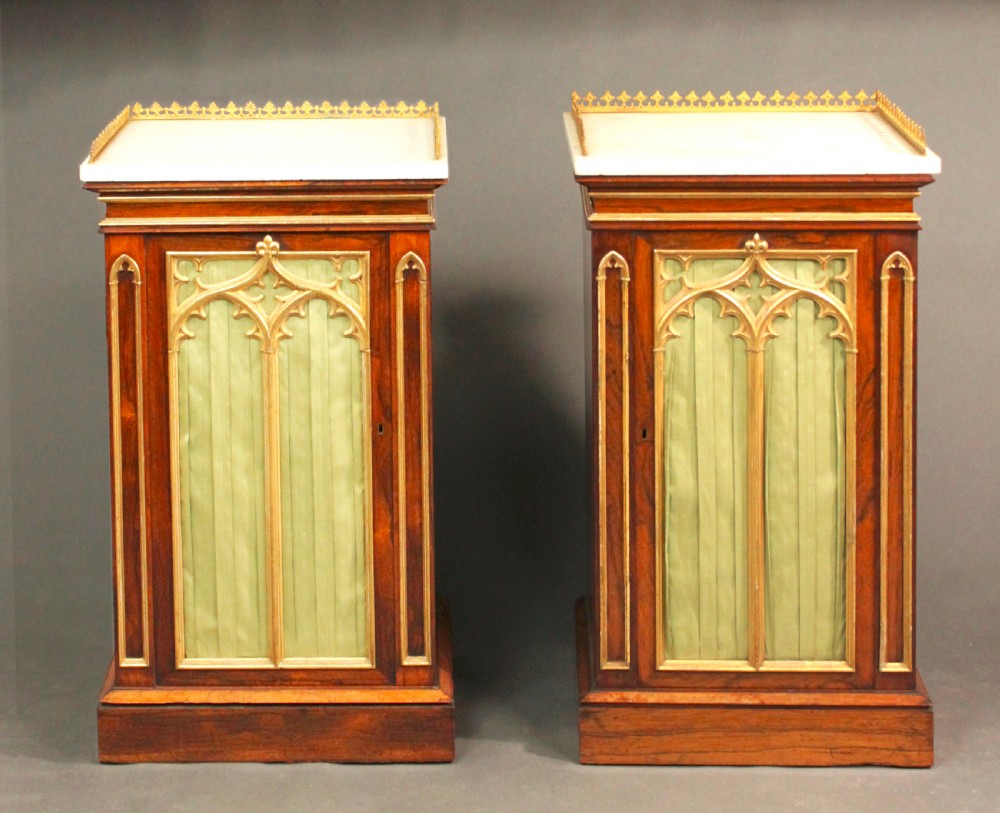 A pair of dark rosewood Regency Gothic pedestal cupboards featuring white marble tops with pierced brass galleries and pleated green silk doors framed by gilt tracery. View II