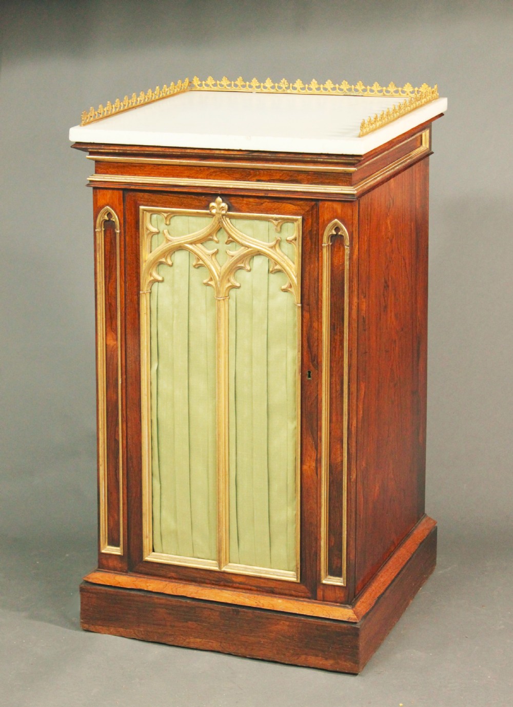 A pair of dark rosewood Regency Gothic pedestal cupboards featuring white marble tops with pierced brass galleries and pleated green silk doors framed by gilt tracery. View III