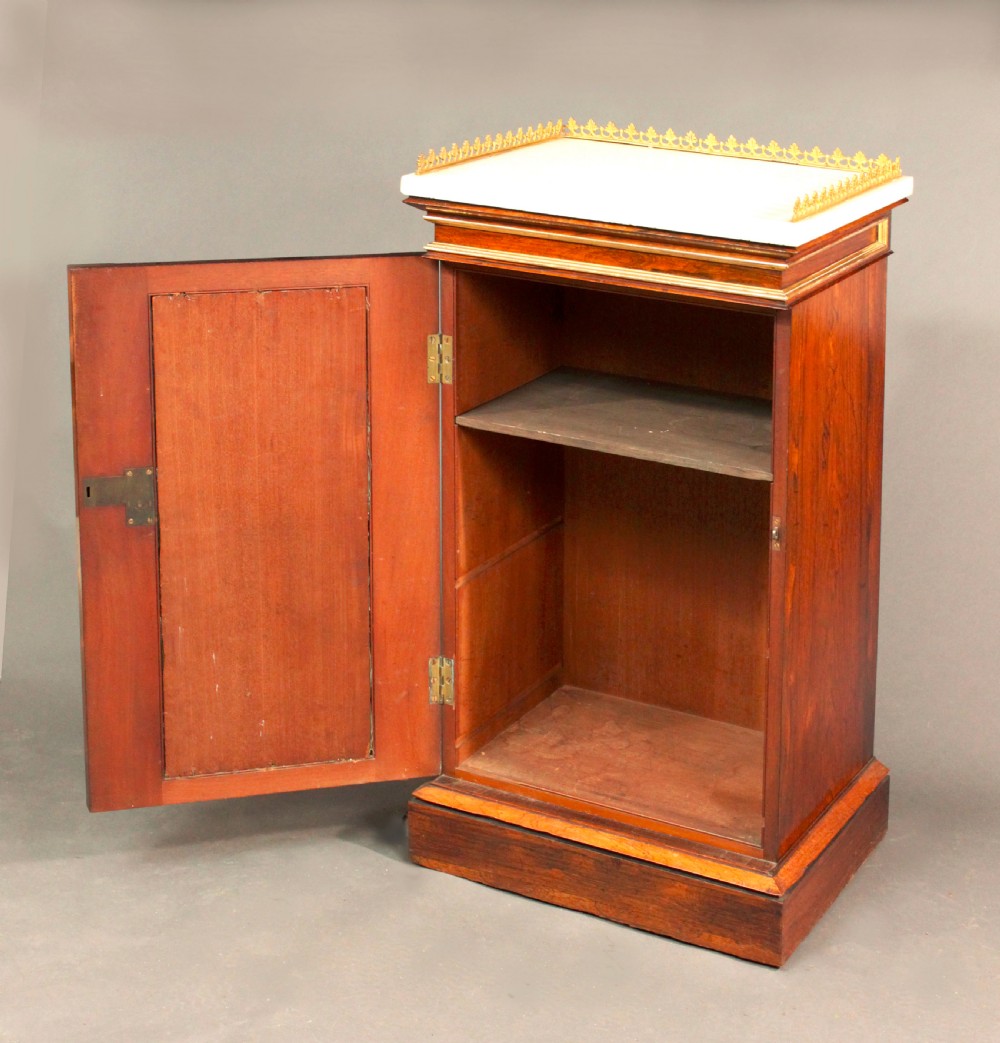 A pair of dark rosewood Regency Gothic pedestal cupboards featuring white marble tops with pierced brass galleries and pleated green silk doors framed by gilt tracery. View IV