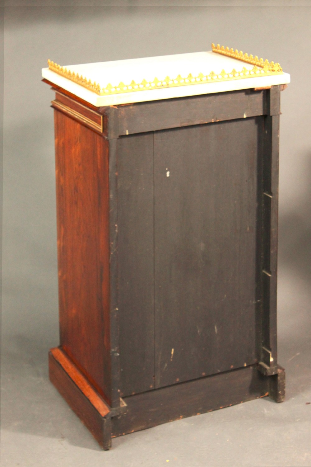 A pair of dark rosewood Regency Gothic pedestal cupboards featuring white marble tops with pierced brass galleries and pleated green silk doors framed by gilt tracery. View VI