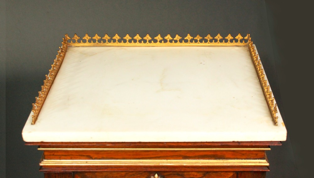 A pair of dark rosewood Regency Gothic pedestal cupboards featuring white marble tops with pierced brass galleries and pleated green silk doors framed by gilt tracery. View VII