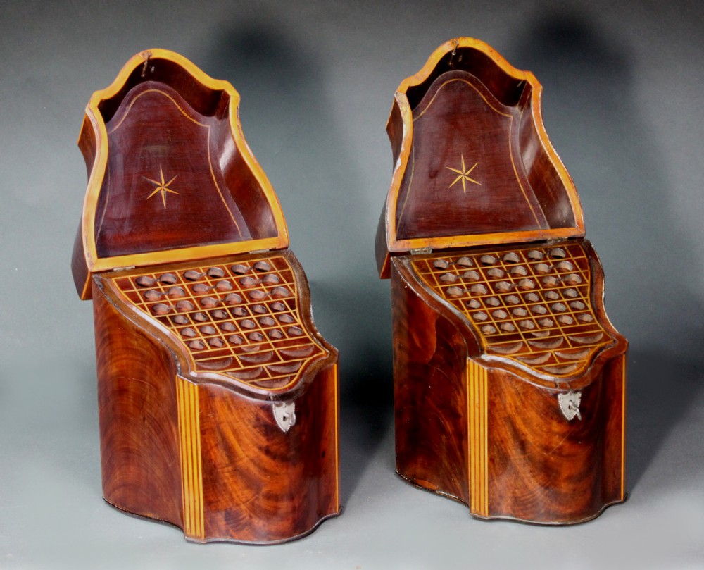 A pair of open Georgian mahogany knife boxes featuring slanted tops, star inlay on the inner lids, and slotted interior cutlery compartments.